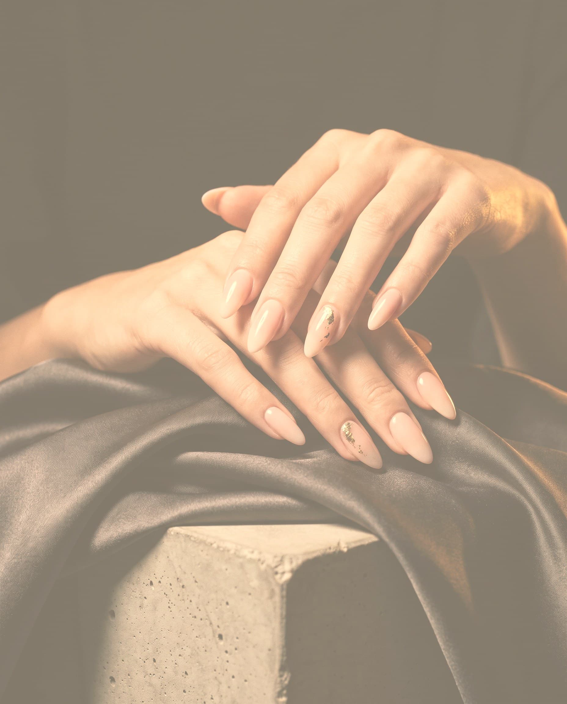 Close-up of hands with soft pink almond nails and a gold accent